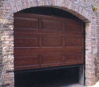 Basculante in legno a cassettoni in apertura sotto un arco in mattoni