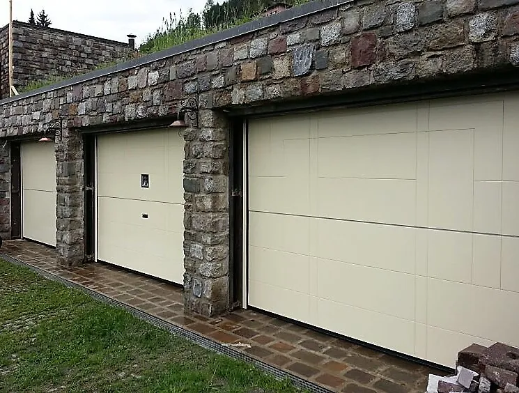 Porte da garage chiare inserite in un muro in pietra